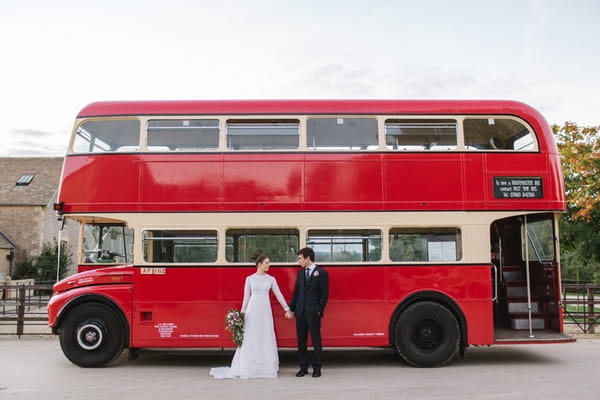 Bride and groom next to red bus