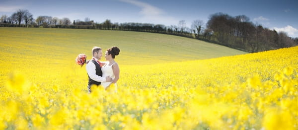 Bride and groom in field of yellow flowers - Picture by Linus Moran Photography