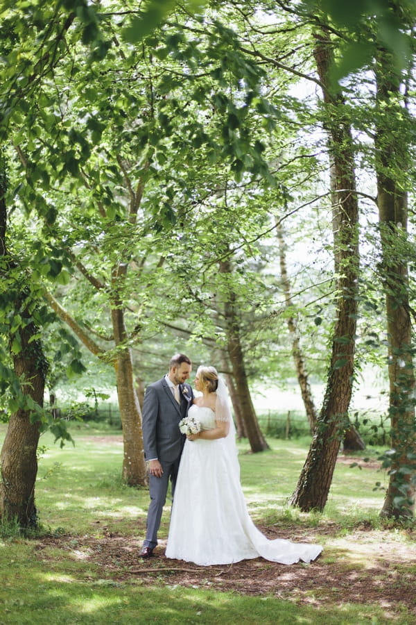 Bride and groom standing amongst trees