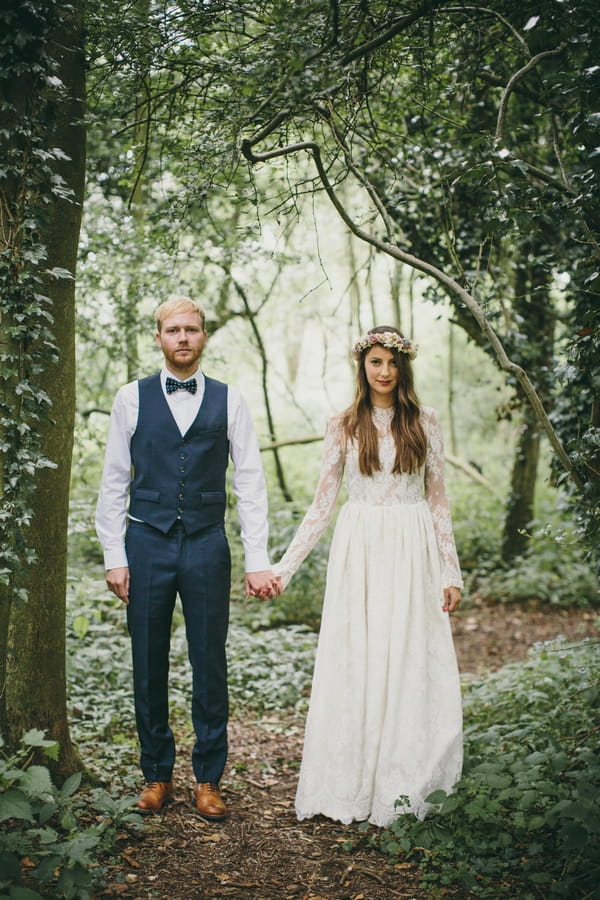 Bride and groom holding hands in woods