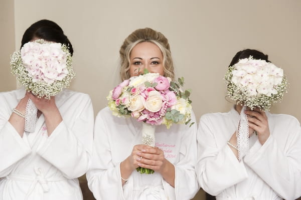 Bride and bridesmaids hiding behind bouquets