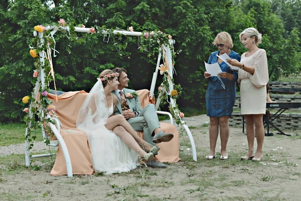 Bride and groom sitting on rocking bench during reading