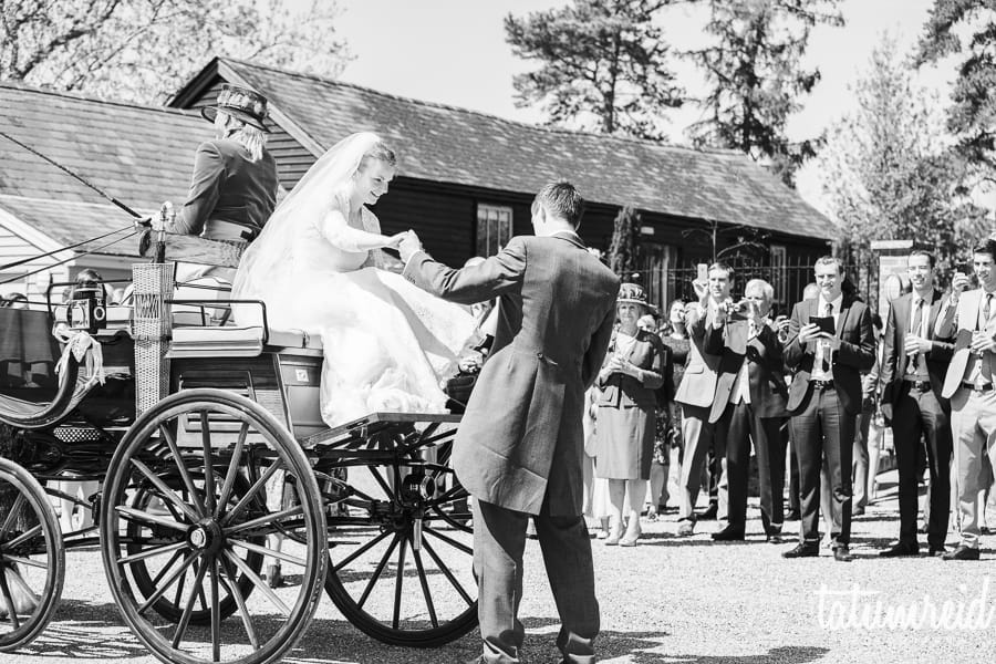 Groom helping bride off of horse and cart