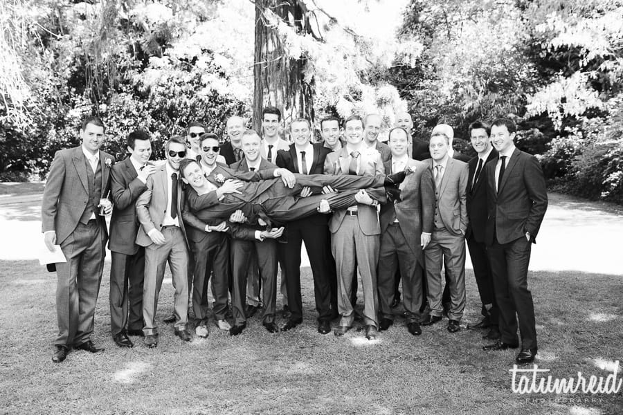 Men at wedding lifting up groom