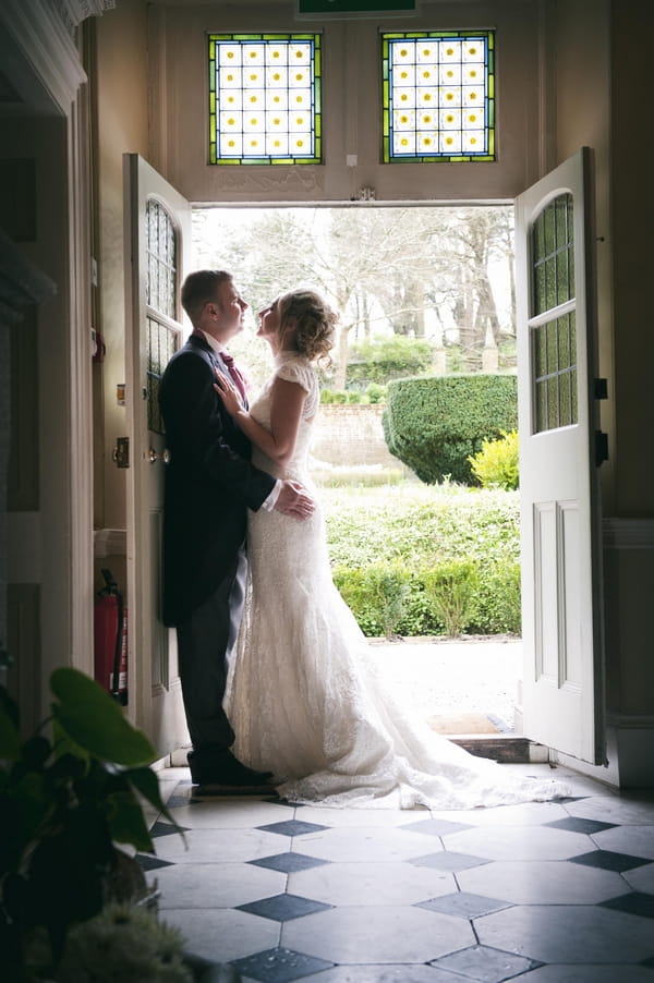 Bride and groom leaning against door