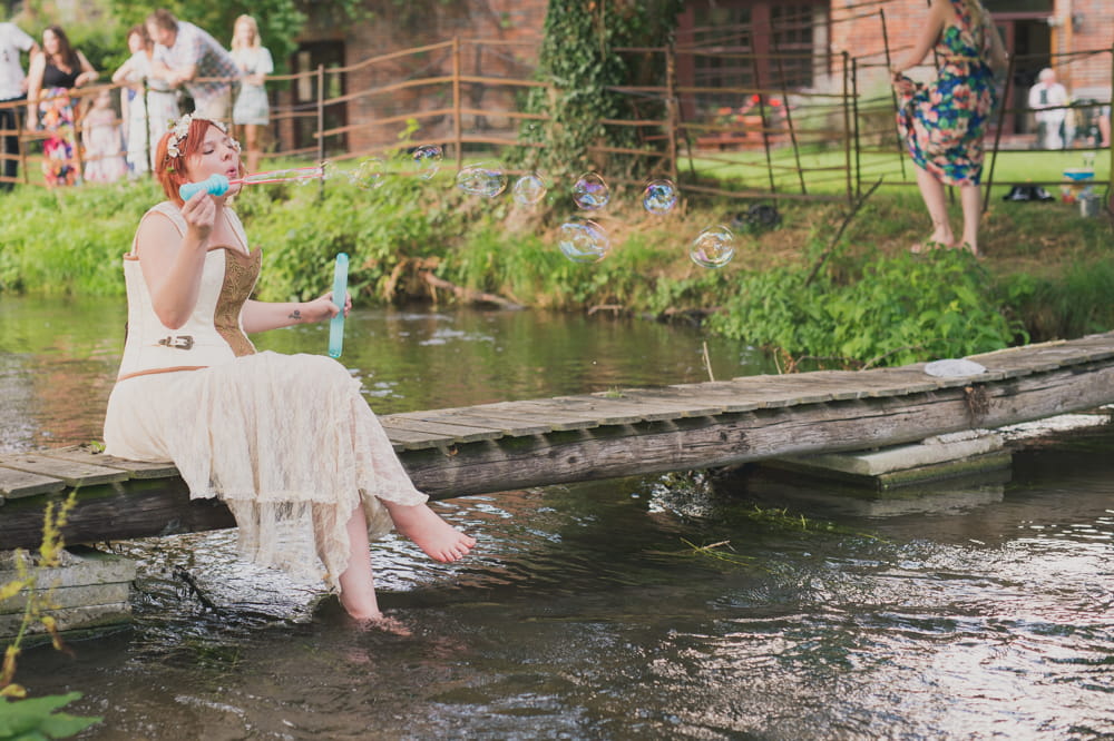 Bride sitting on bridge over stream