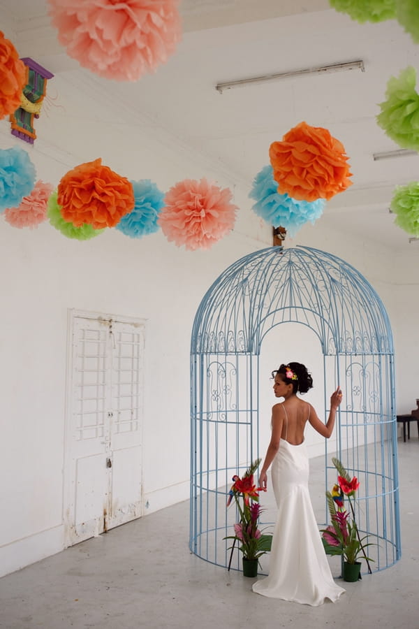 Bride standing next to large bird cage