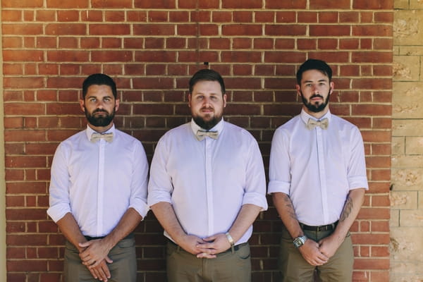 Groomsmen standing against wall