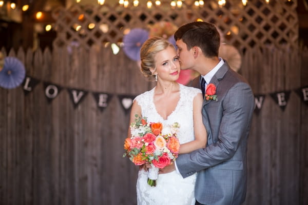 Groom kissing bride on cheek