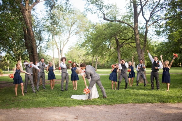 Bride and groom kissing in front of wedding party