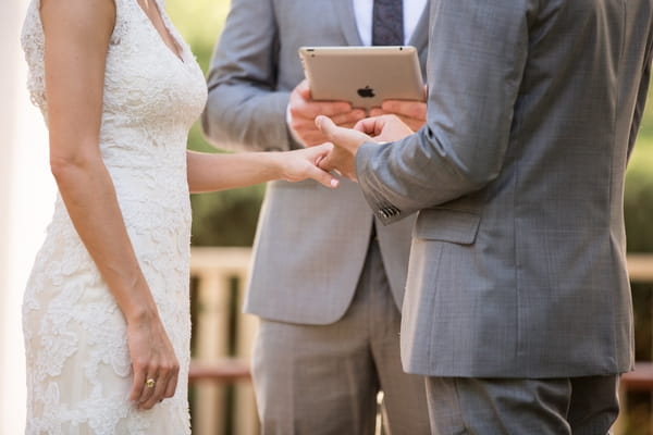 Groom putting ring on bride's finger