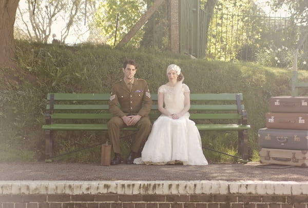 1920's bride and groom sitting on bench at train station