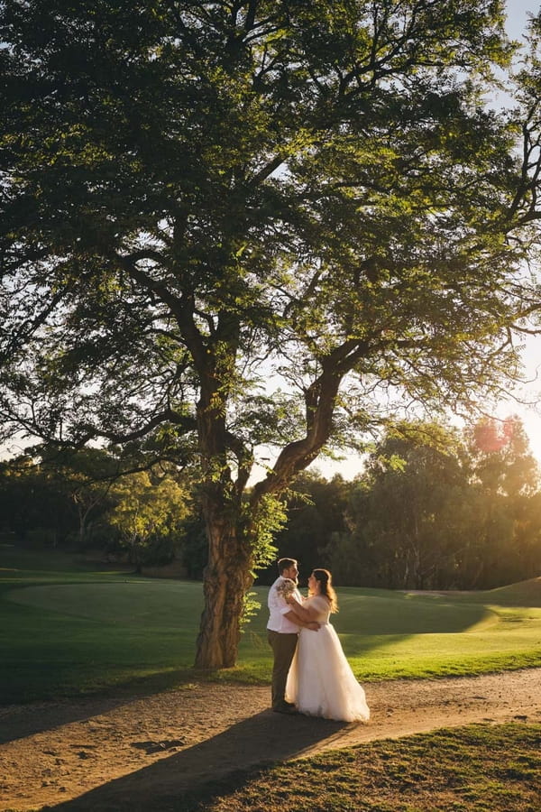 Bride and groom under tree