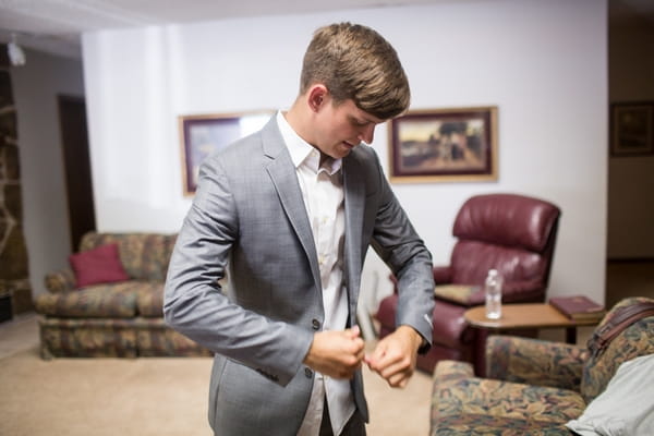 Groom putting jacket on