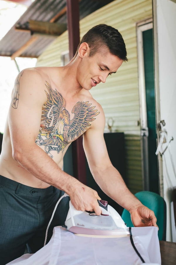 Man with large tattoo ironing