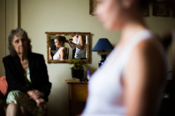 Reflection in mirror of bridesmaid having hair done