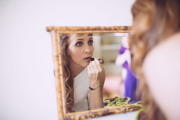 Bride putting on lipstick in mirror