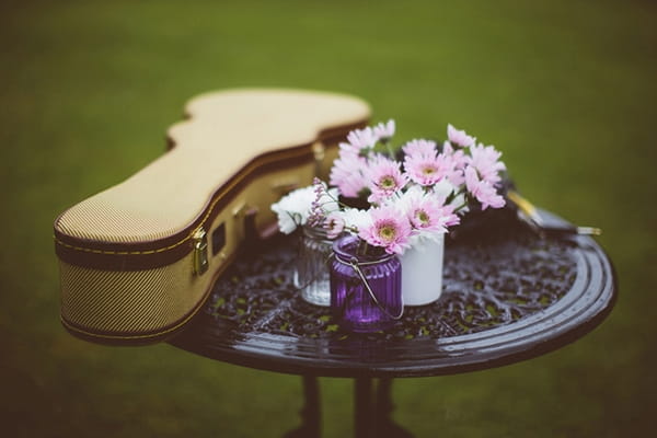 Guitar case and flowers on table