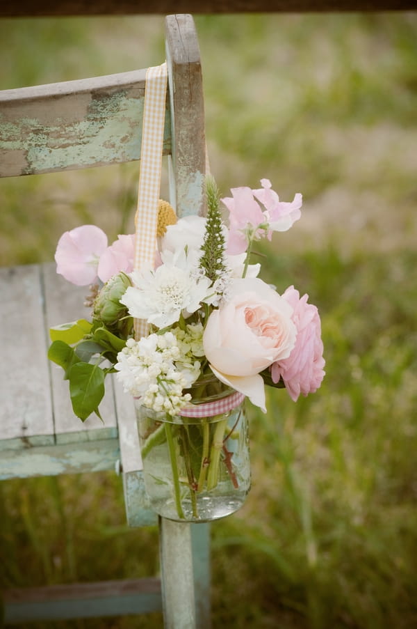 Flowers in jar on end of chair
