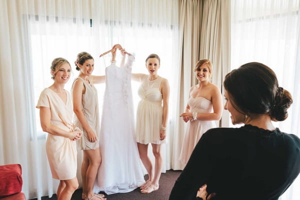 Bridesmaids holding up bride's dress