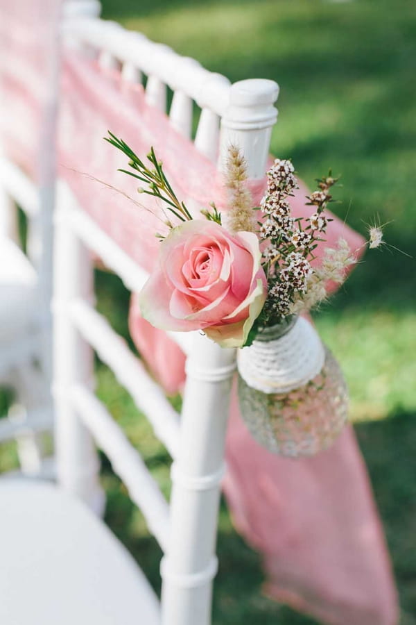 Small vase of flowers tied to chair end