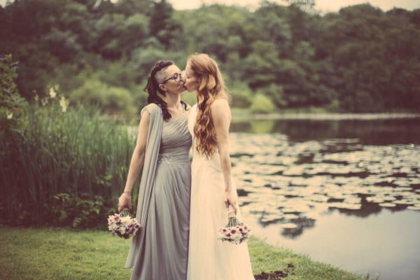 Brides kissing by lake