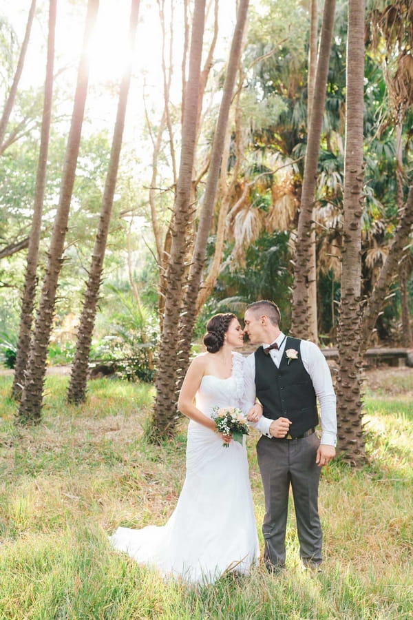 Bride and groom kiss in woods