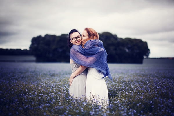 Brides kissing in field