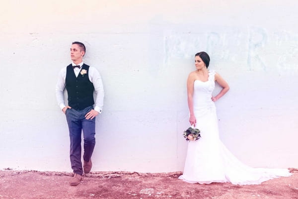 Bride and groom against wall