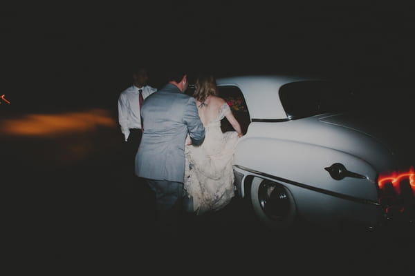 Bride and groom getting in wedding car