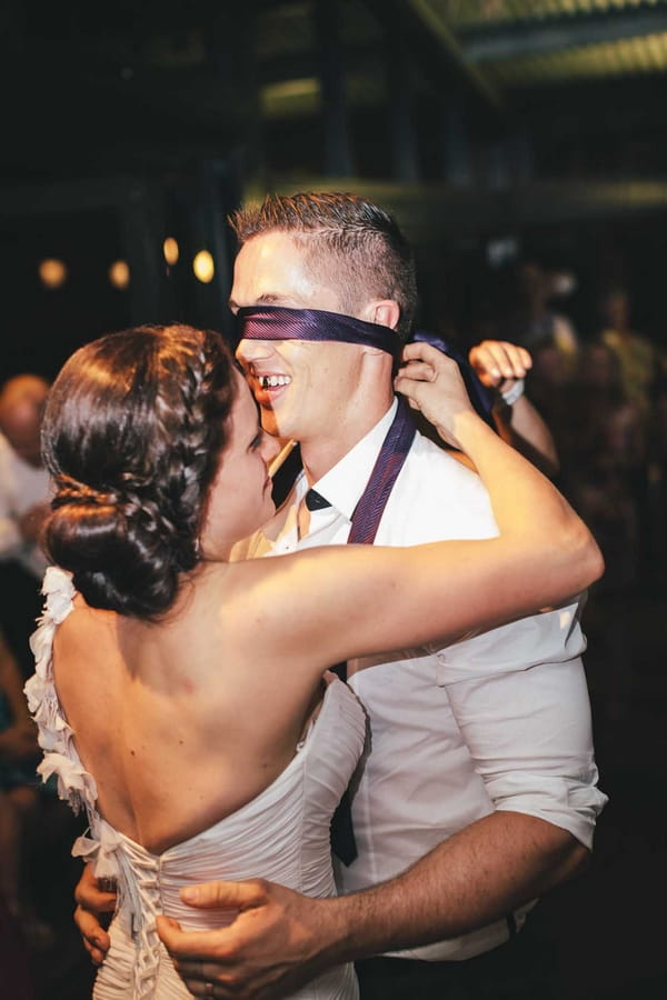 Bride tying tie over groom's eyes