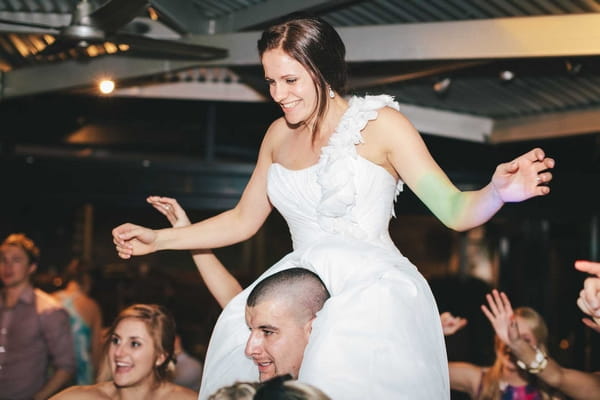 Bride sitting on man's shoulders