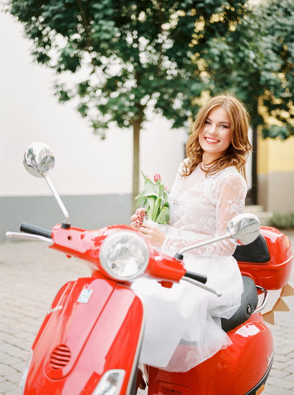 Bride sitting on red Vespa