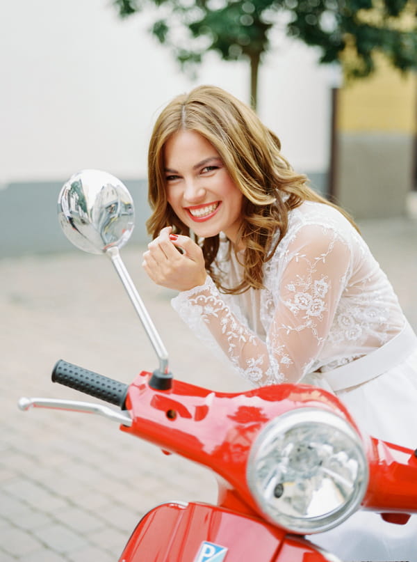 Bride leaning on red Vespa