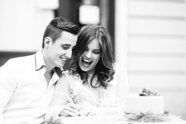 Bride and groom sitting at table writing