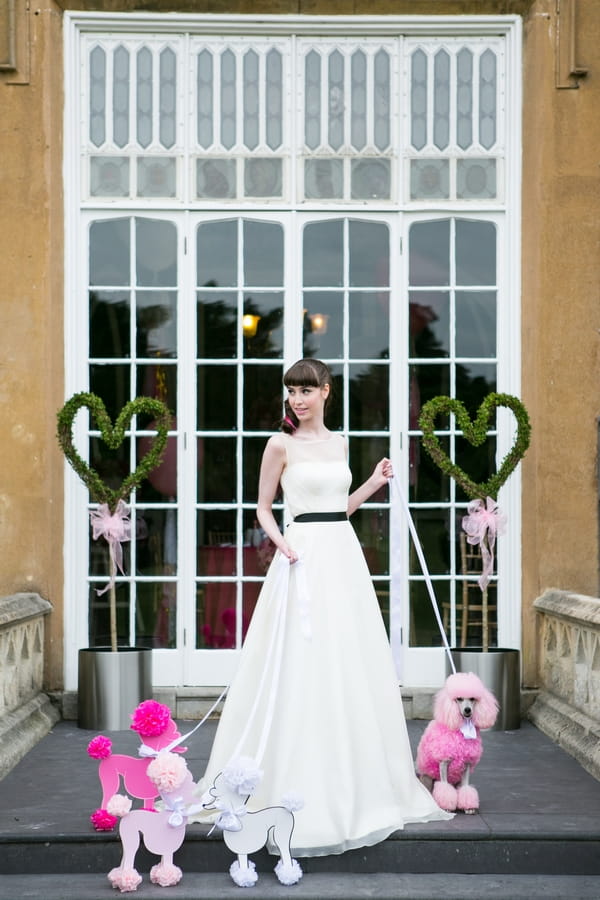 Bride standing with pink poodle