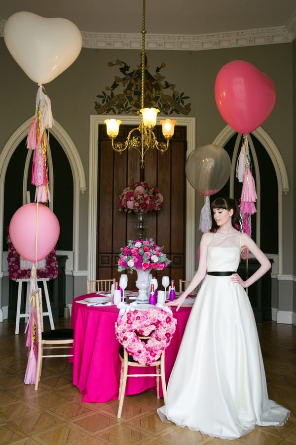 Bride standing next to table with pink styling