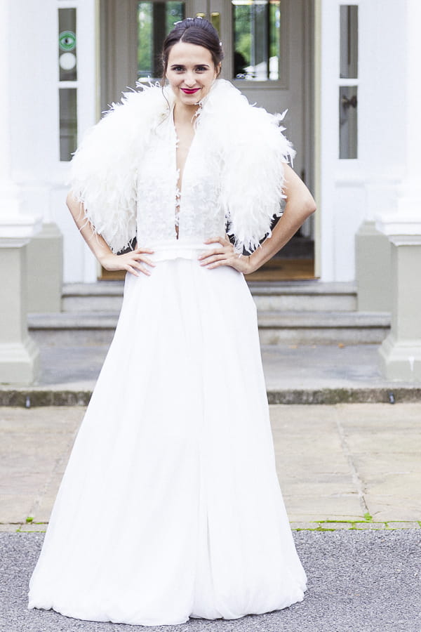 Bride with hands on hips wearing feather shrug