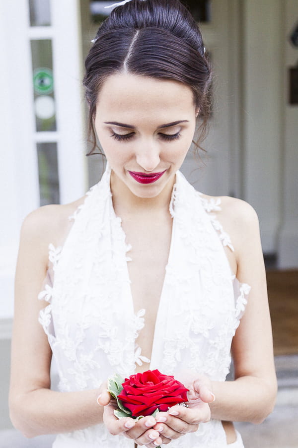 Bride looking down at red rose in hands