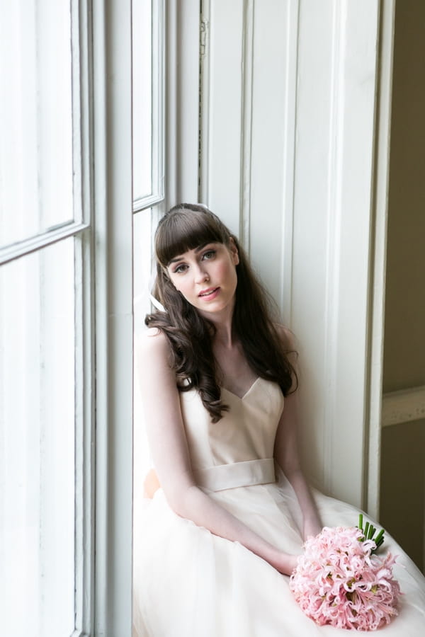 Bride sitting on window ledge