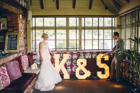 Bride and groom in room with large illuminated letters
