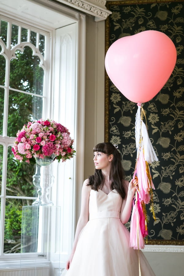 Bride holding pink heart balloon