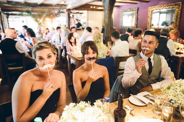 Wedding guests putting moustaches to their faces