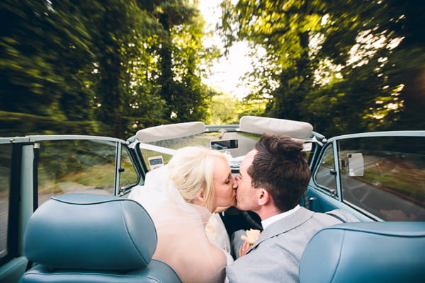 Bride and groom kiss in car