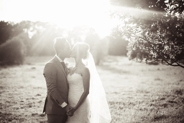 Bride and groom kiss in hazy sunshine