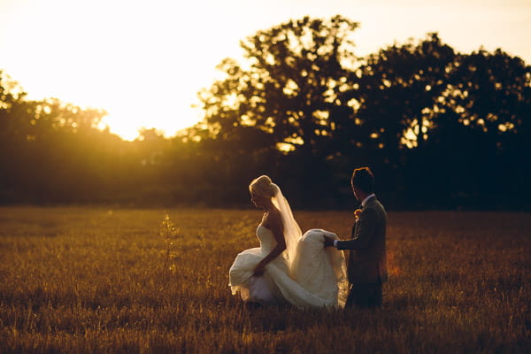 Groom holding train of bride's dress