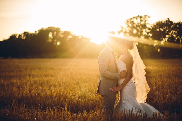 Bride and groom in field in hazy sunshine