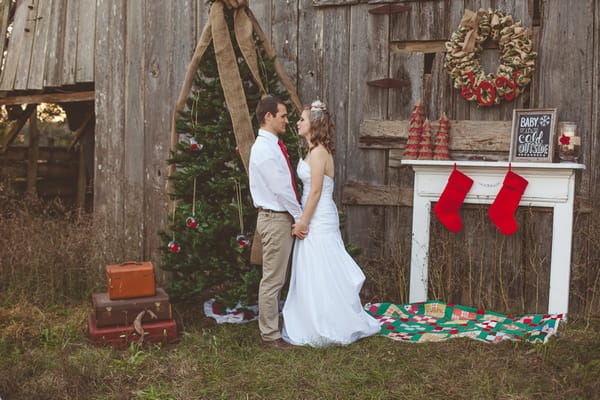Bride and groom holding hands in front of Christmas tree