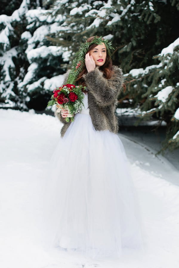 Bride with fur shrug standing in snow
