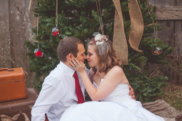 Bride and groom about to kiss in front of Christmas tree